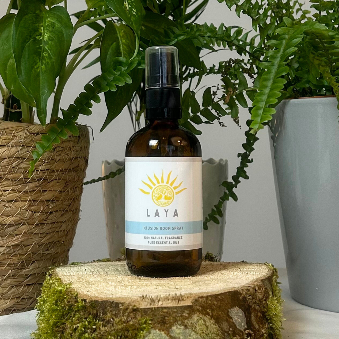 Infusion Room Spray by Laya displayed on natural wood, in 100ml amber glass bottle.