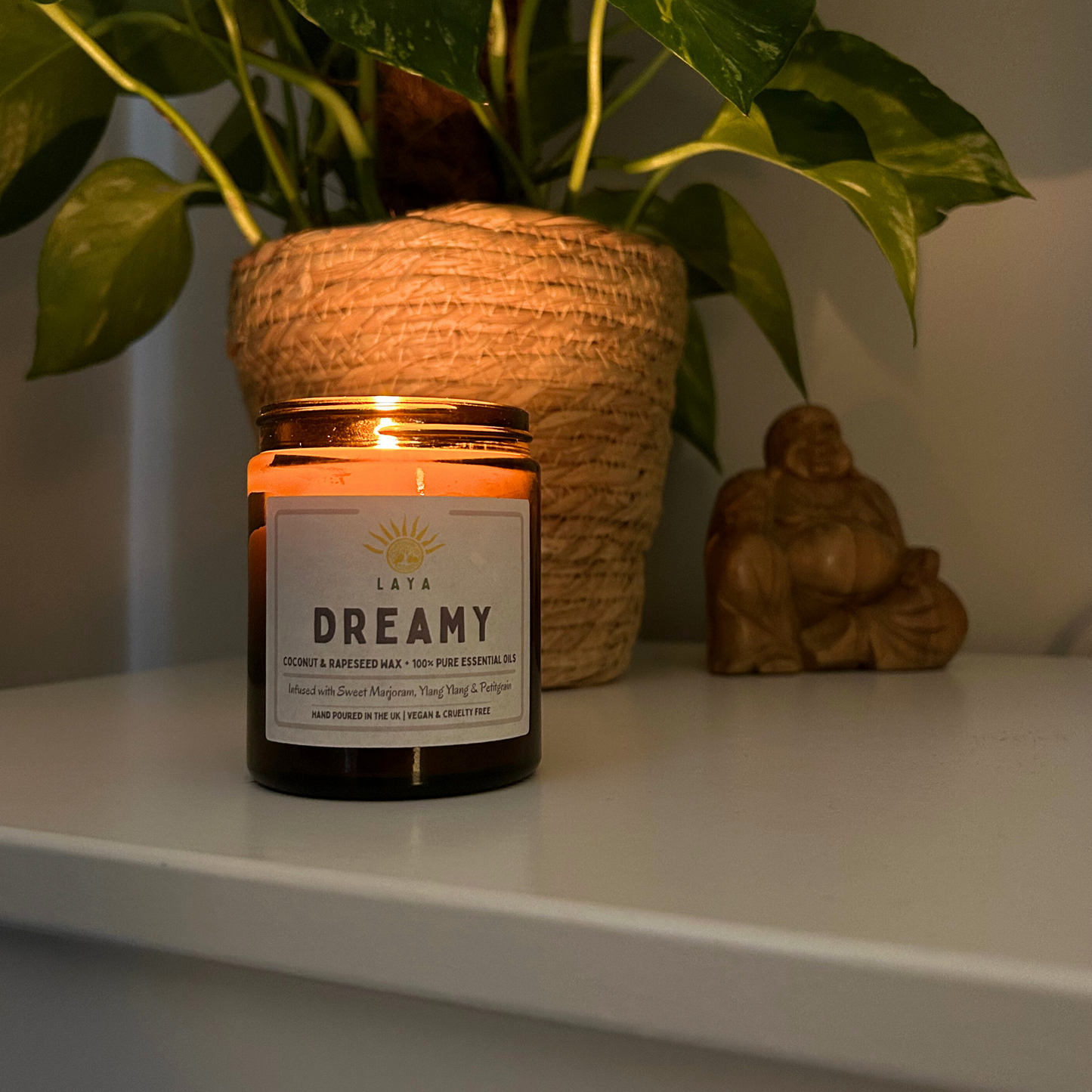 Natural coconut & rapeseed dreamy candle, gently flickering in a serene, dimly lit bedroom on side table.