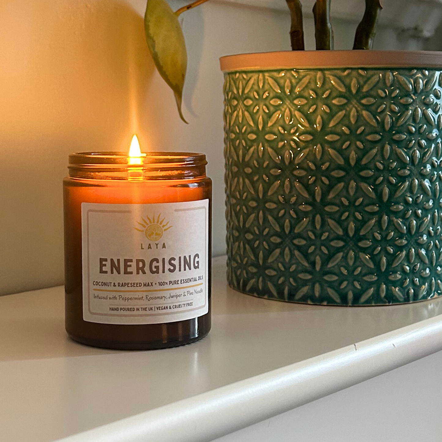 Lit energising candle by Laya gently flickering in a peaceful space, made from natural coconut & rapeseed waxes.